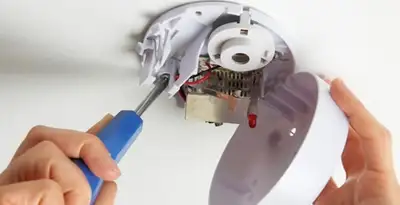 Certified technician wiring smoke detector during installation in Clearwater, FL
